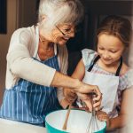 Grandma and granddaughter baking in a kitchen.