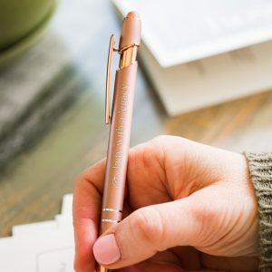 Lady with a Legacy rose gold writing pen in a hand writing on paper