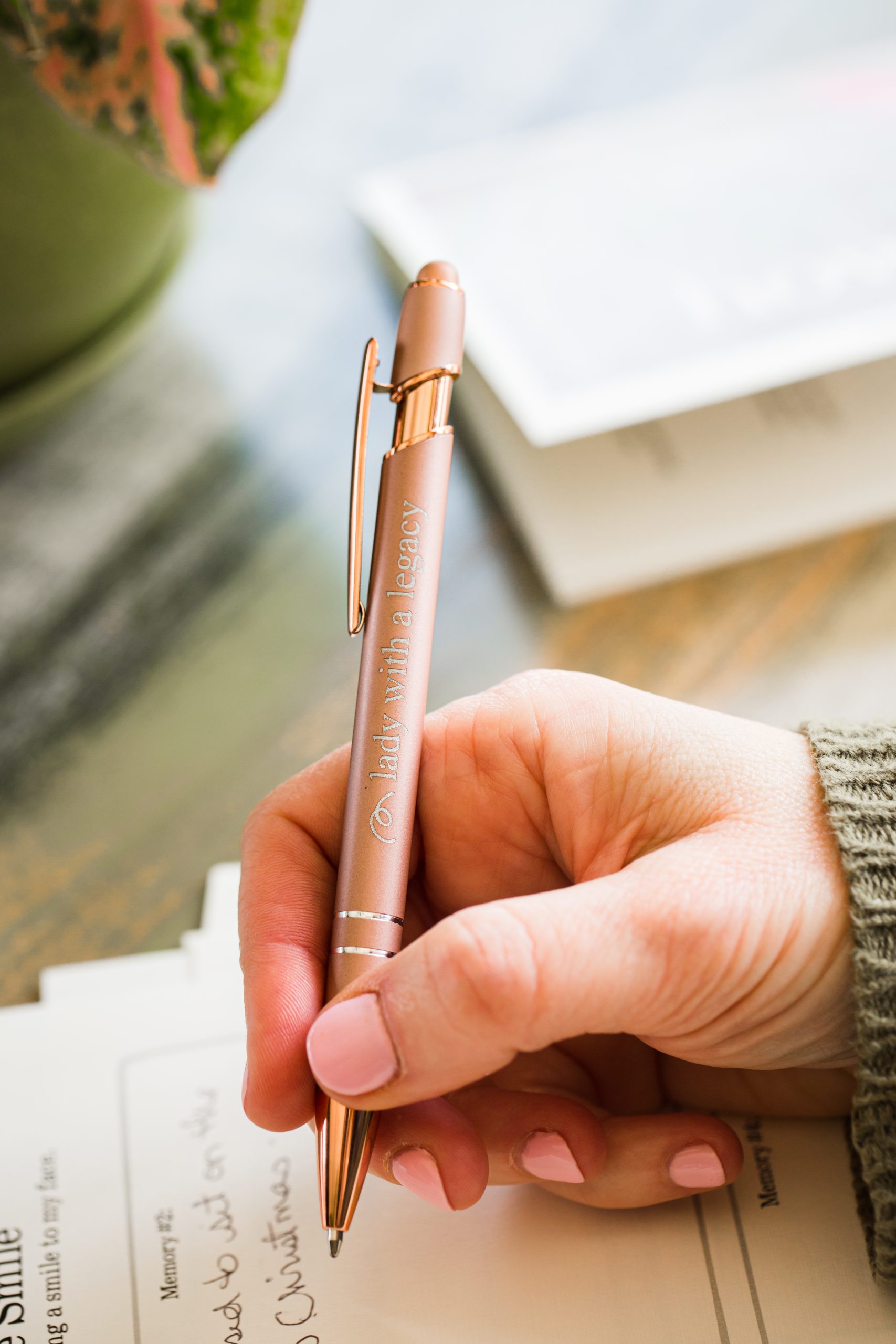 Lady with a Legacy rose gold writing pen in a hand writing on paper
